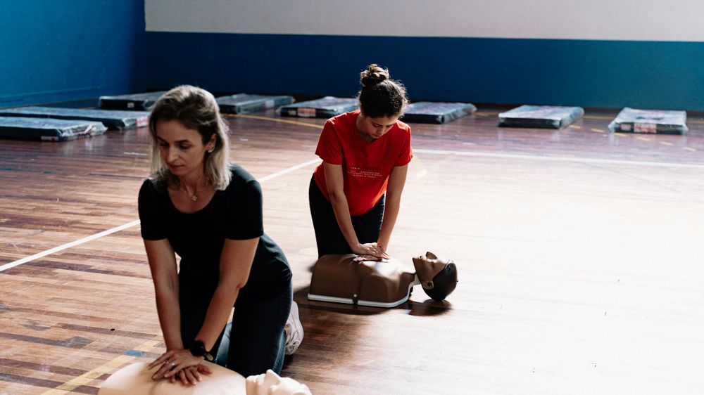 Stock photograph of two learners practicing chest compressions on separate CPR manikins indoors